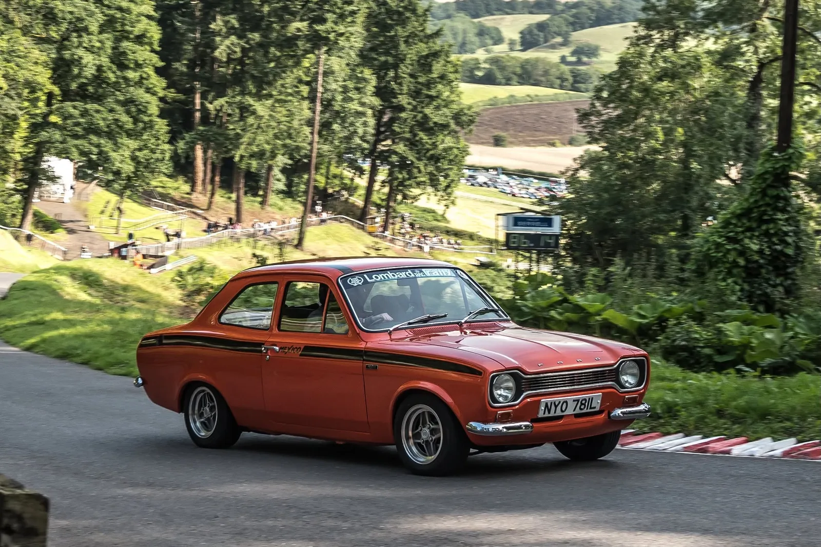 Adam driving his orange Ford Escort Mk1 Mexico up the Shelsley Walsh hill climb, with the entire car in view